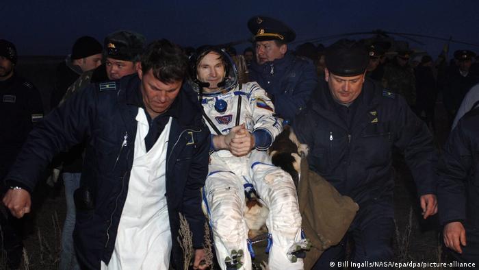 Astronaut Marcos Pontes being carried by men after landing back on Earth