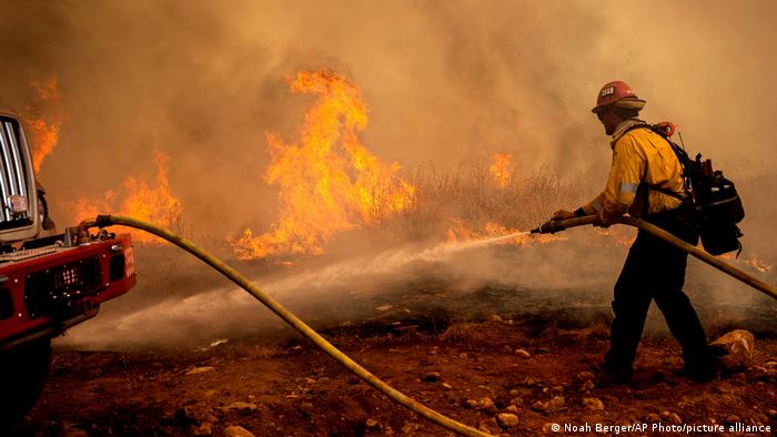 A firefighter sprays water while trying to keep the Electra Fire from spreading in the Pine Acres community of Amador County