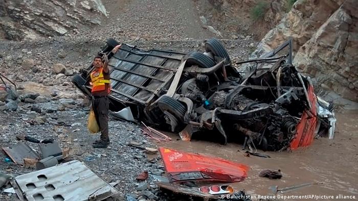 A rescue worker stands next to the wreck of a passenger bus, in Zhob, Baluchistan province, in southwest Pakistan