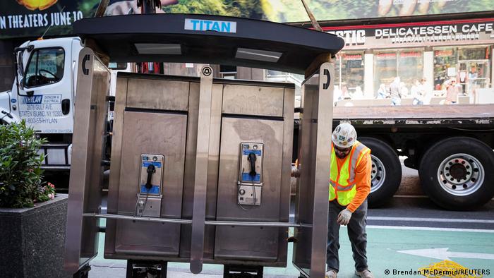 أحد العمال يقوم بإزالة كابينة تحتوي على هاتفين عموميين. أحد العمال يقوم بإزالة كابينة تحتوي على هاتفين عموميين.