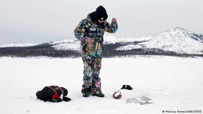 Darcel Noah, 13 Jahre, angelt Fische durch ein Loch in der dicken Eisdecke.